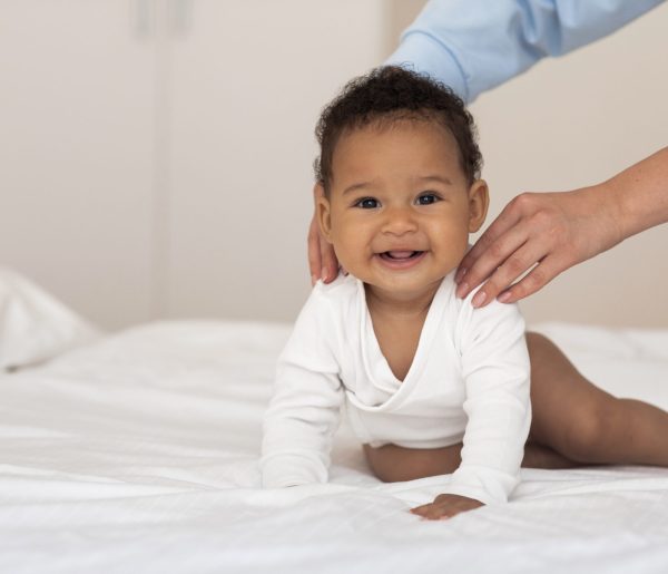 Cute Little Black Baby Relaxing On Bed While His Mom Making Massage Cute Little Black Baby Relaxing On Bed While His Mom Making Massage, Unrecognizable Woman Stroking Shoulders Of Her Adorable African American Infant Son, Taking Care About Child At Home